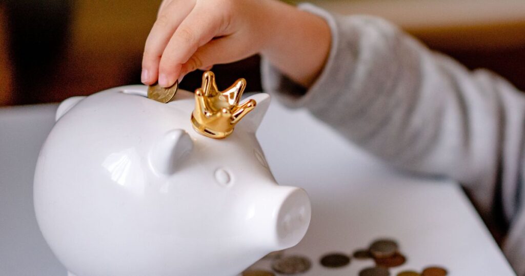 子どもが貯金箱にコインを入れてお金の使い方を学んでいる様子